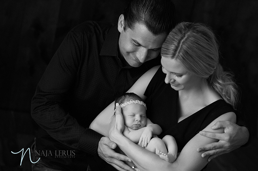 Black and white image parents posing with new baby