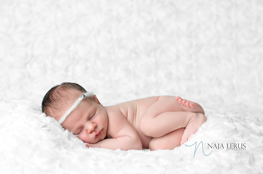 Newborn baby girl photographed on white rose backdrop